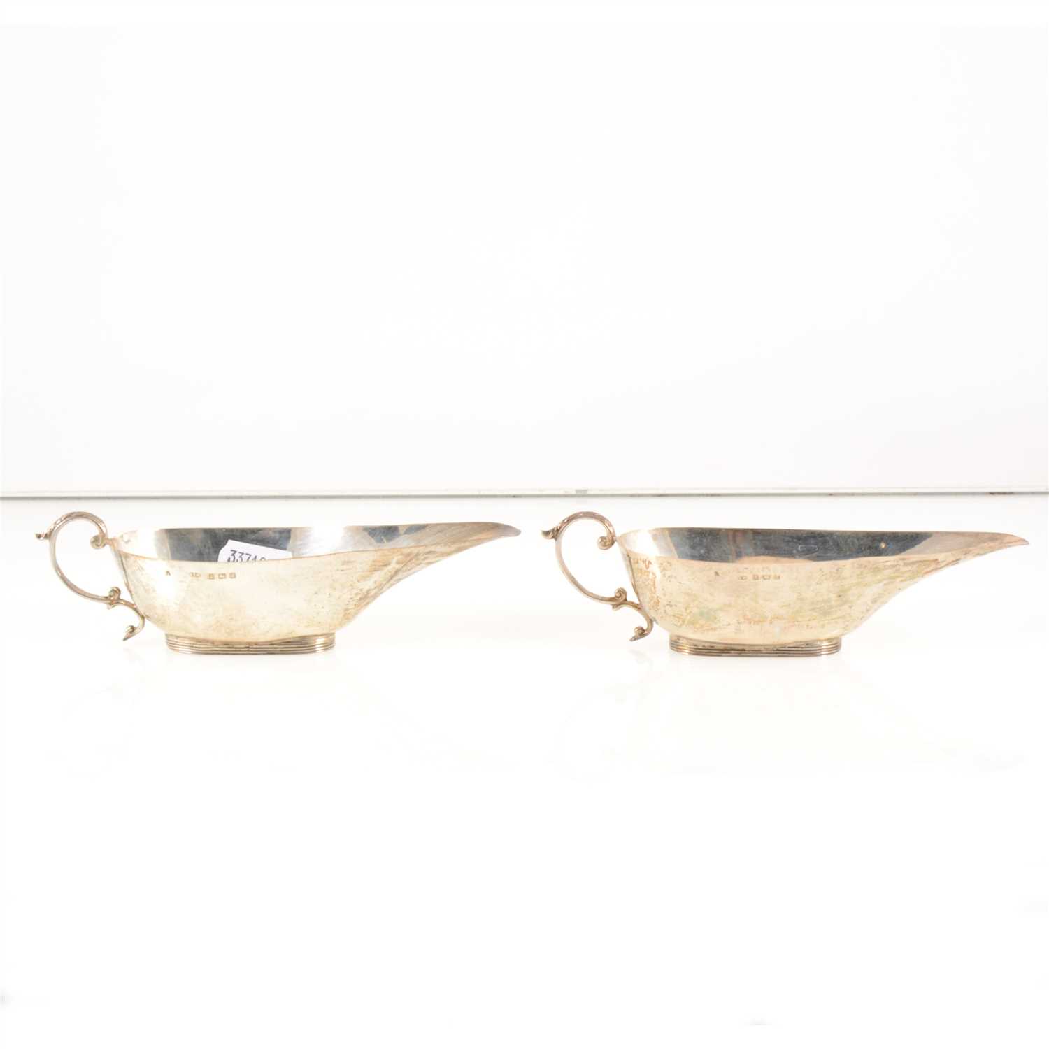 Lot 178 - A pair of small Edwardian silver sauceboats by Henry Matthews, Birmingham 1909, plain oval form with scrolled handles, length 16cm, cased, weight approx. 2.7oz.