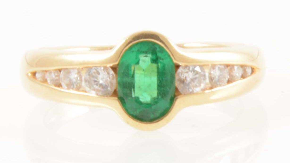 Lot 208 - An 18 carat yellow gold ring set with an emerald and eight diamonds.