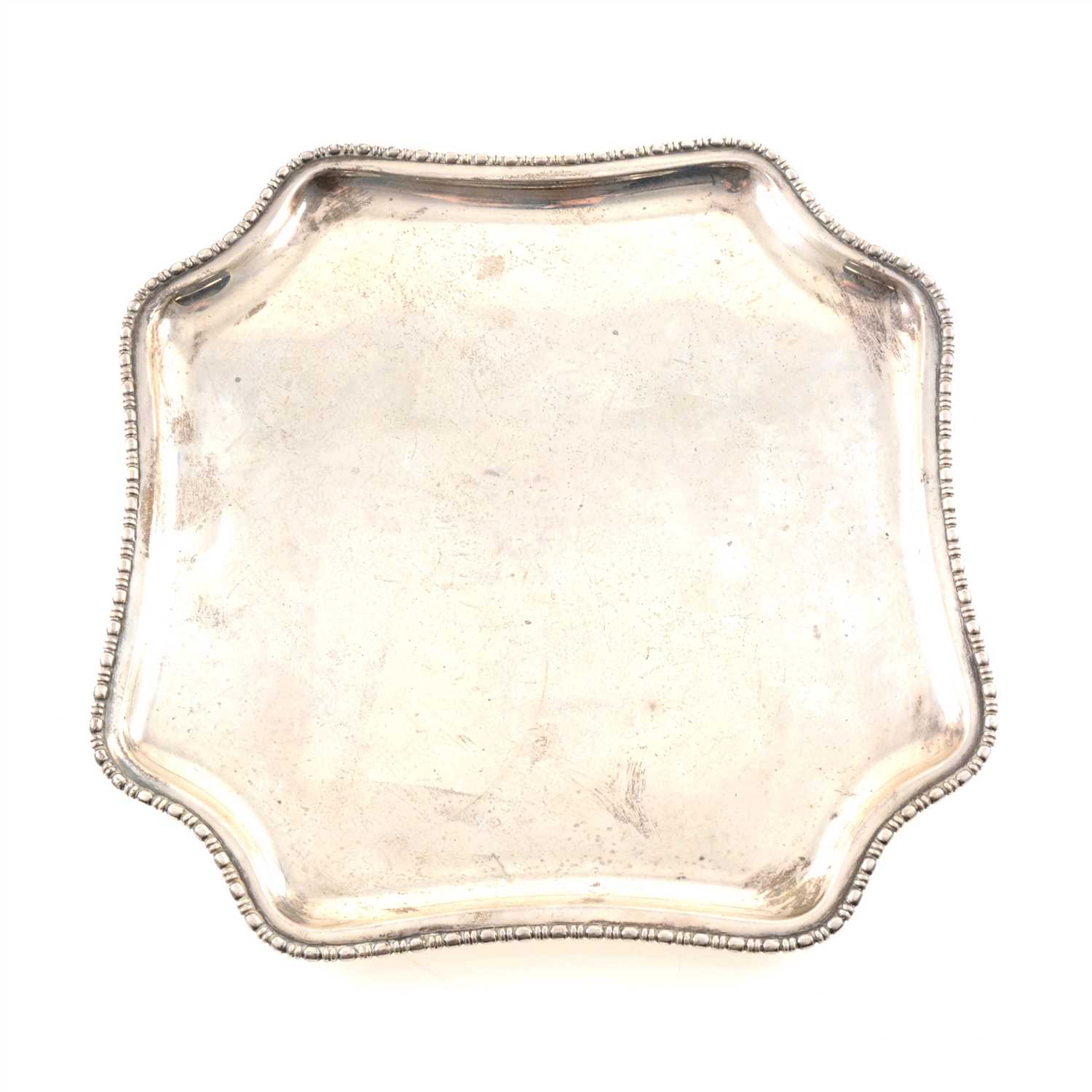 Lot 246 - A silver salver by Atkin Brothers, square shape with curved corners and beaded edge, on four round feet, Sheffield 1927, 24.5cm diameter, weight approx. 16.8oz.