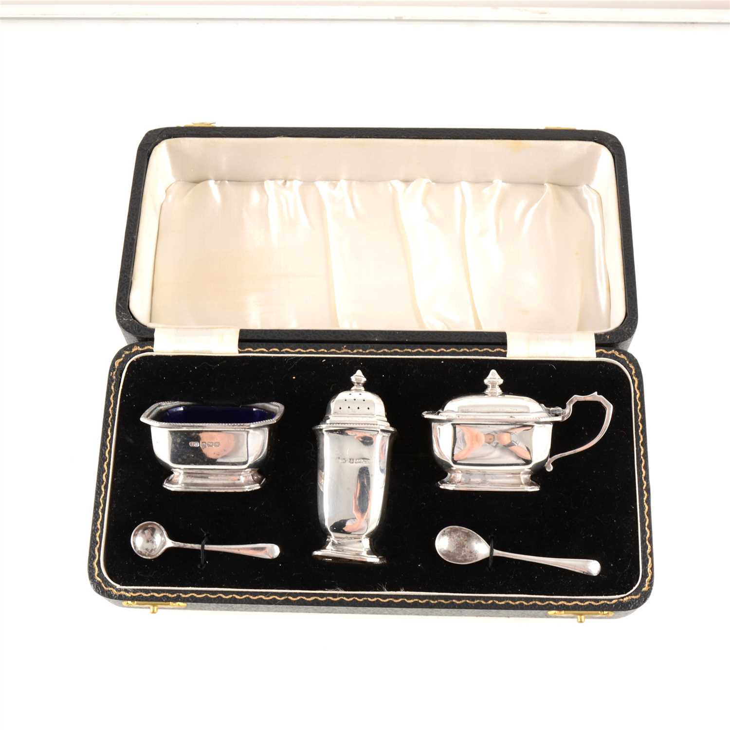 Lot 179 - A silver condiment set by William Suckling Ltd, Birmingham 1946, comprising salt with blue glass liner, pepperette and mustard, with two spoons, cased, weight approx. 3.7oz.