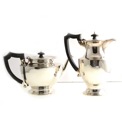 Lot 197 - A George V silver teapot and hot water jug by Wakely & Wheeler, circular form with ebony handles and finials, London 1923, gross weight approx. 37.9oz.