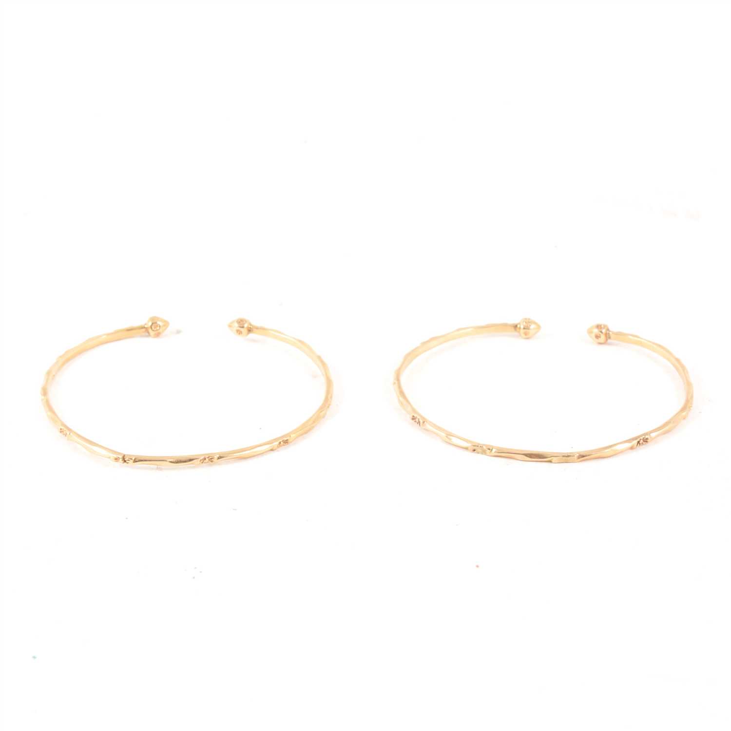 Lot 241 - A pair of yellow metal open ended torque bangles, marked "10K", 2.2mm width, total weight approx. 17.3gms.