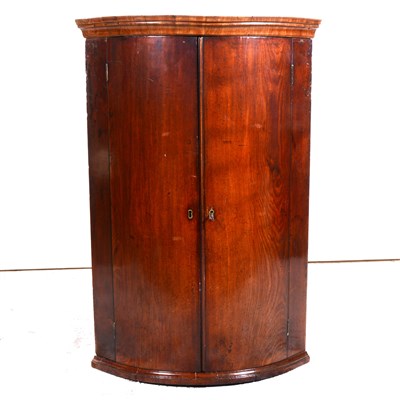 Lot 426 - George III mahogany cylinder front hanging corner cupboard, cavetto moulded cornice, two doors enclosing three shelves with spice drawers under, height 105cm.