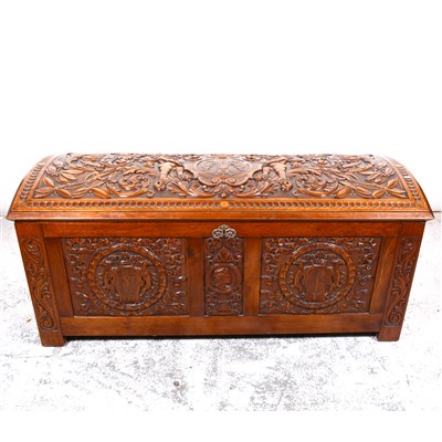 Lot 517 - South American hardwood coffer, domed top, all over carved in higher relief, with cherub acanthus scrolls, front panel with portrait roundel, crests, linen-fold panelled sides, the top significant...