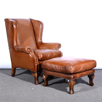 Lot 523 - A tan leather wing-back easychair, and matrching footstool.