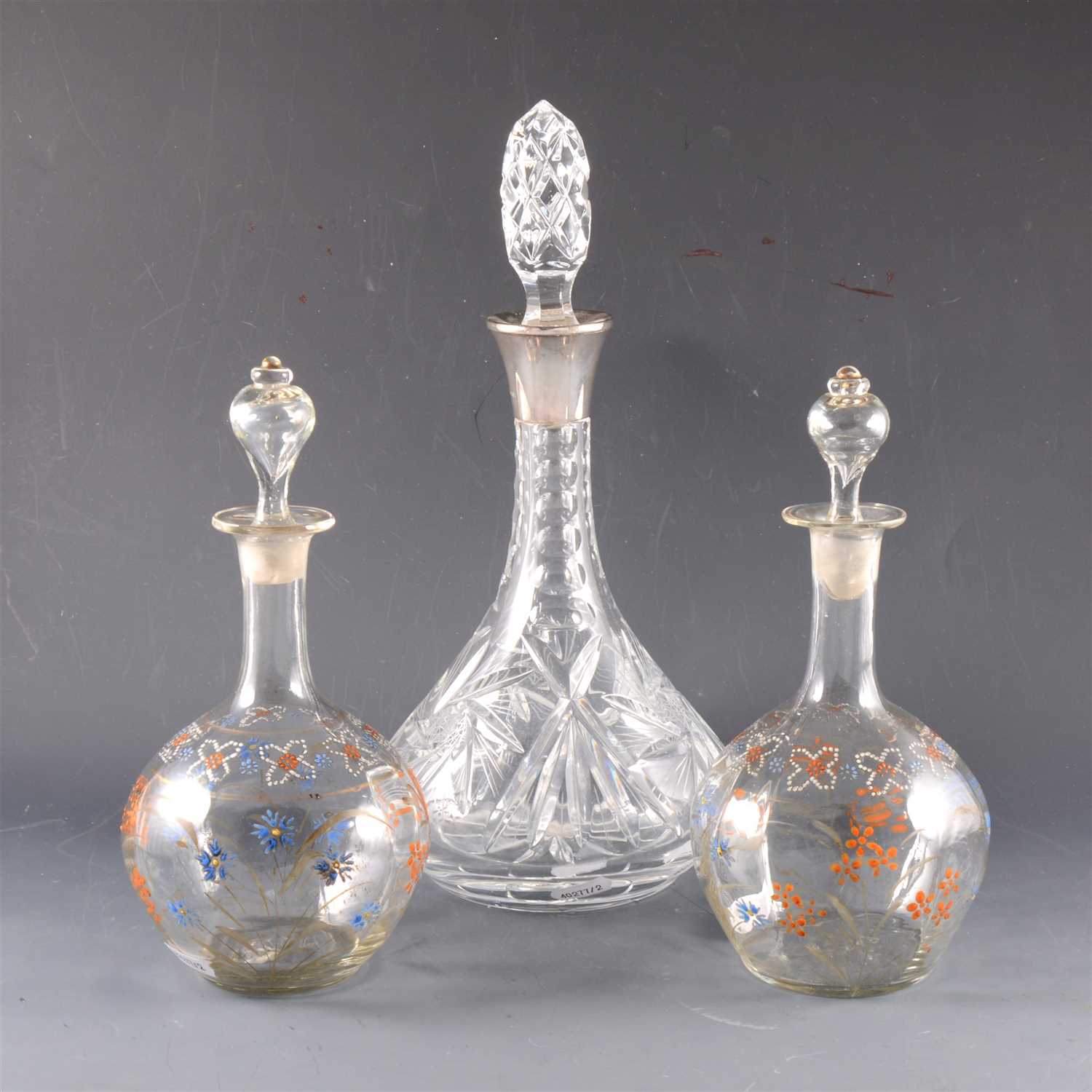 Lot 11 - A crystal decanter with silver collar and two bulbous decanters with enamelled decoration.