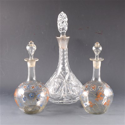 Lot 11 - A crystal decanter with silver collar and two bulbous decanters with enamelled decoration.