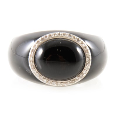 Lot 282 - A black domed ring with diamond set circle.