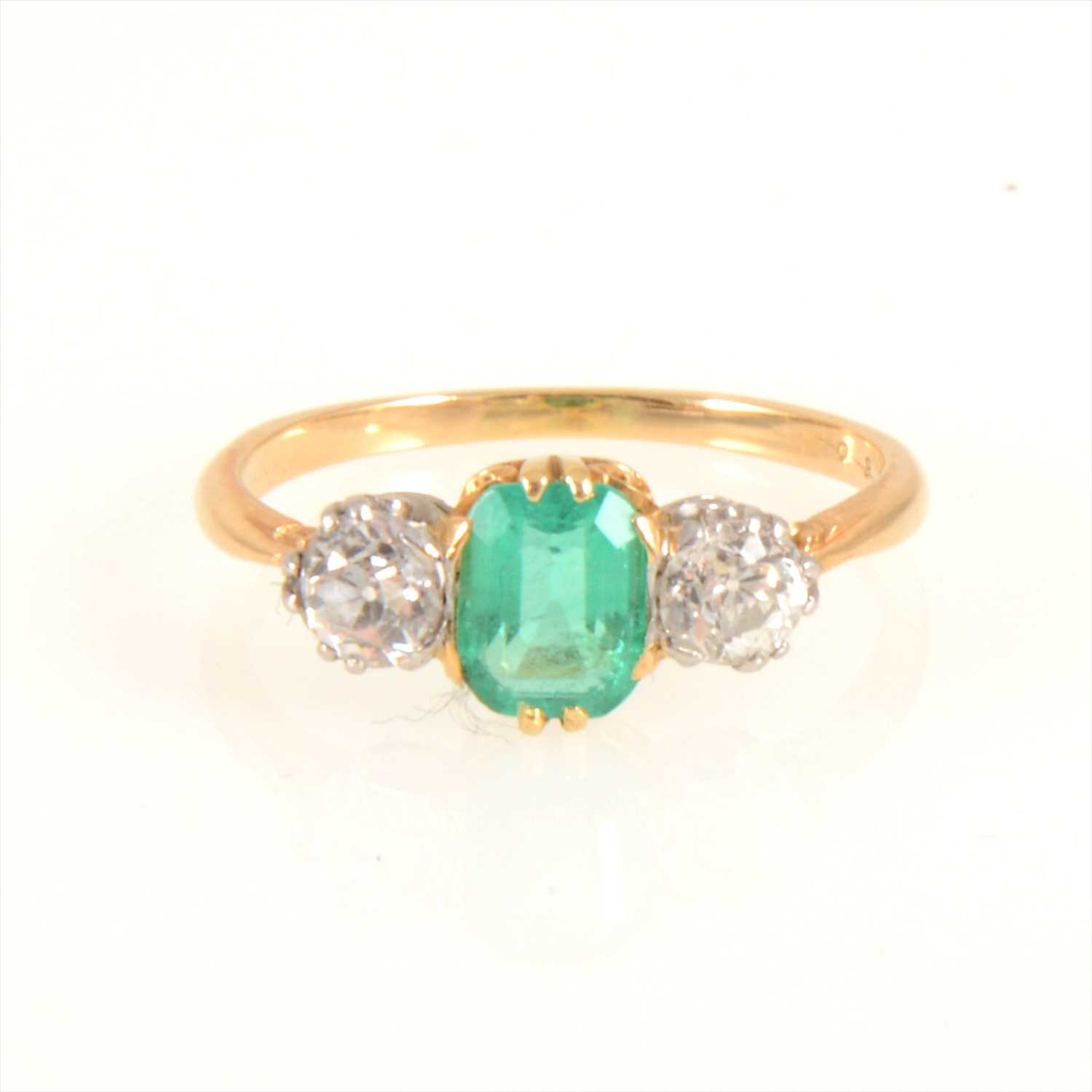 Lot 674 - An emerald and diamond three stone ring.