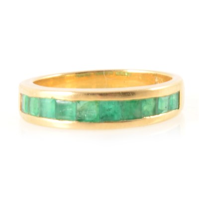 Lot 390 - An emerald half eternity ring.