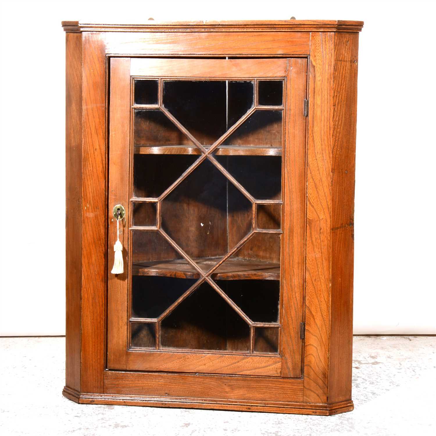 Lot 429 - A Victorian elm hanging corner cupboard, with glazed panelled door enclosing serpentine shelves, height 99cm.