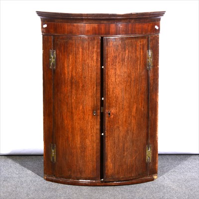 Lot 635 - A George III oak and mahogany cylinder front hanging corner cupboard, ...