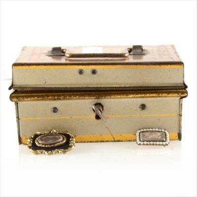 Lot 337 - A locking tin box containing two Victorian mourning brooches.