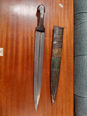 Lot 242 - An North African knife, 41cm fullered blade, in a metal covered sheath.