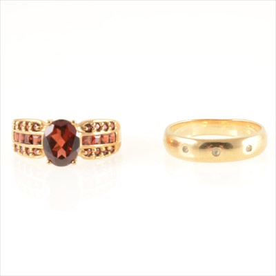 Lot 297 - A 9 carat gold band and 9 carat gold garnet set dress ring.