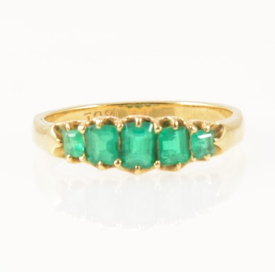 Lot 1269 - An emerald five stone half hoop ring.