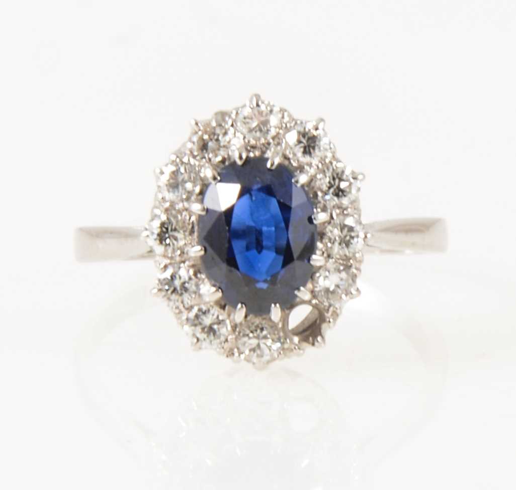 Lot 23 - A sapphire and diamond oval cluster ring.