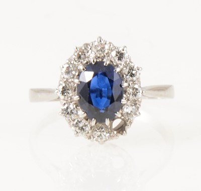 Lot 23 - A sapphire and diamond oval cluster ring.