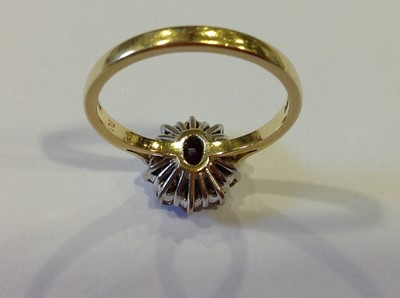 Lot 26 - A ruby and diamond oval cluster ring.