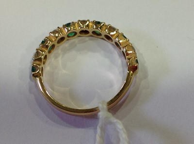 Lot 32 - An emerald and diamond half eternity ring.
