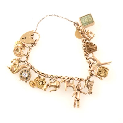 Lot 372 - A yellow metal charm bracelet with sixteen charms plus one loose charm.