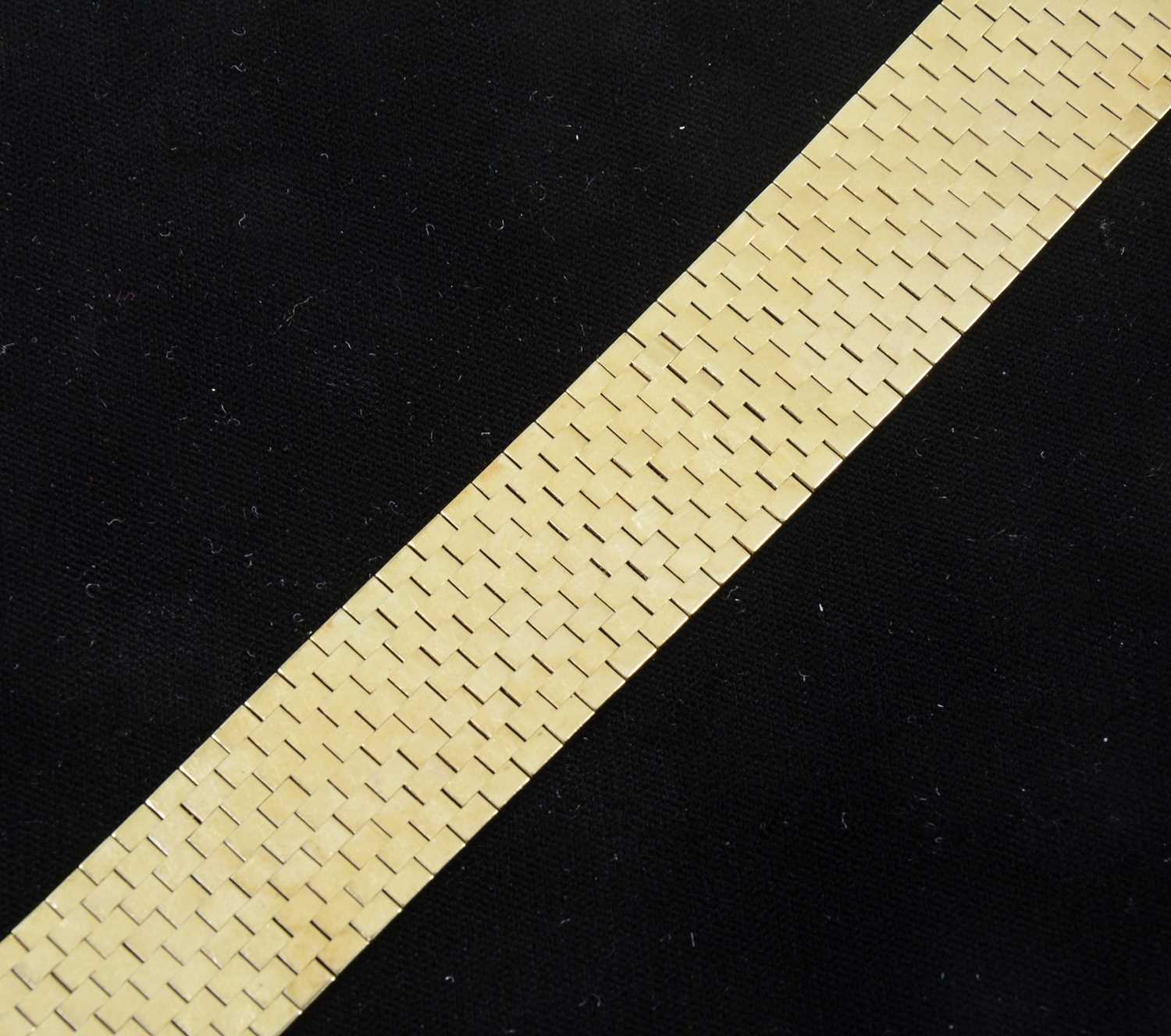 Lot 87 - A yellow metal 26mm wide flexible brick construction bracelet.