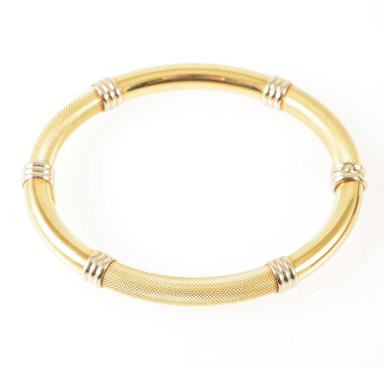 Lot 107 - A modern yellow and white metal half hinged bangle marked 750.