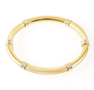 Lot 107 - A modern yellow and white metal half hinged bangle marked 750.