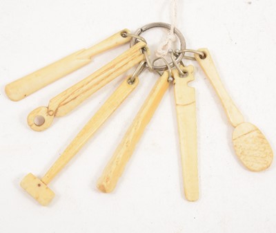 Lot 1168A - A carved bone teething ring, in the shape of carpenter’s tools, a club and a cricket bat, 9cm.