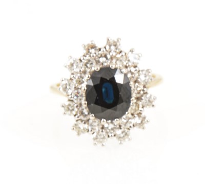 Lot 1262 - A sapphire and diamond oval cluster ring.