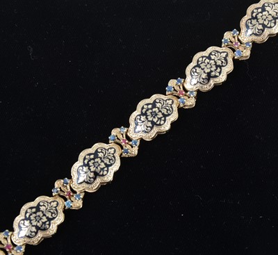 Lot 1305 - A 14 carat gold bracelet decorated in black enamel with sapphires and rubies.