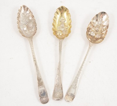 Lot 1191 - Three Georgian silver berry spoons with later decoration.