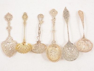 Lot 1201 - Six ornate silver and white metal sugar sifting spoons.