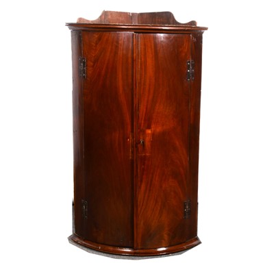 Lot 565 - A Georgian mahogany bowfront hanging corner...