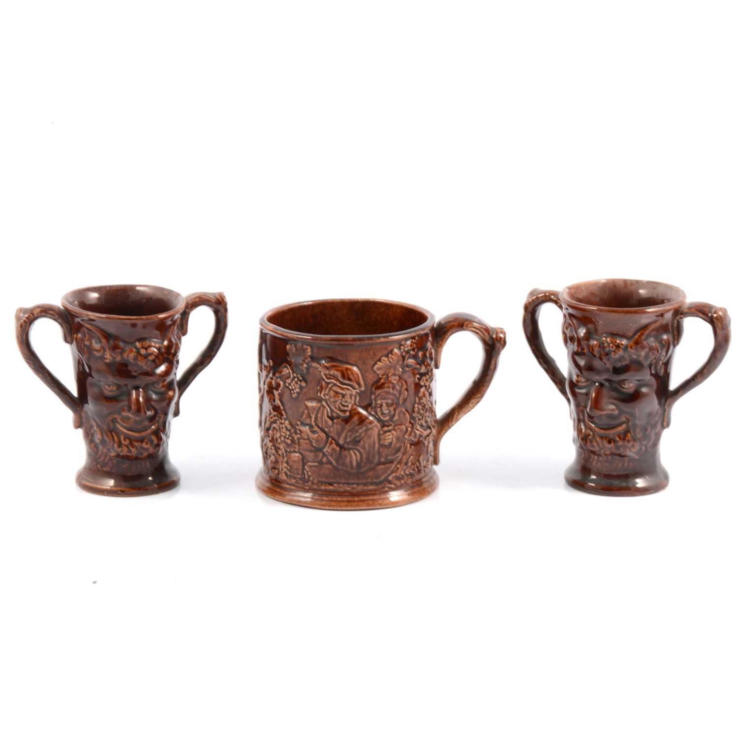 Lot 27 - Staffordshire treacle-glazed frog mug and pair of Bacchus mask Loving Cups.