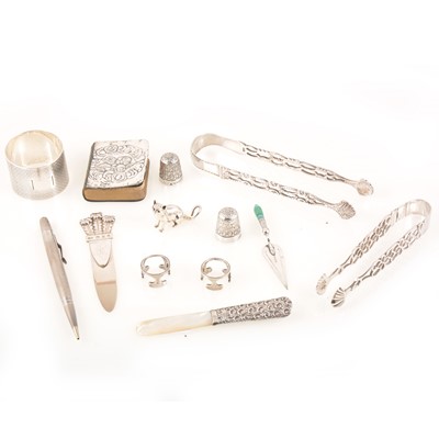 Lot 227 - A tray of silver collectables, napkin ring, sugar tongs, propelling pencil, thimbles.