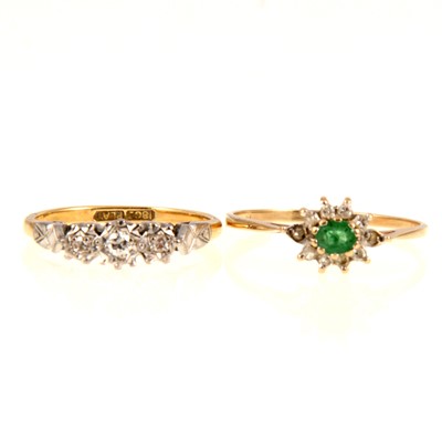 Lot 232 - A diamond three stone ring and an emerald cluster ring.