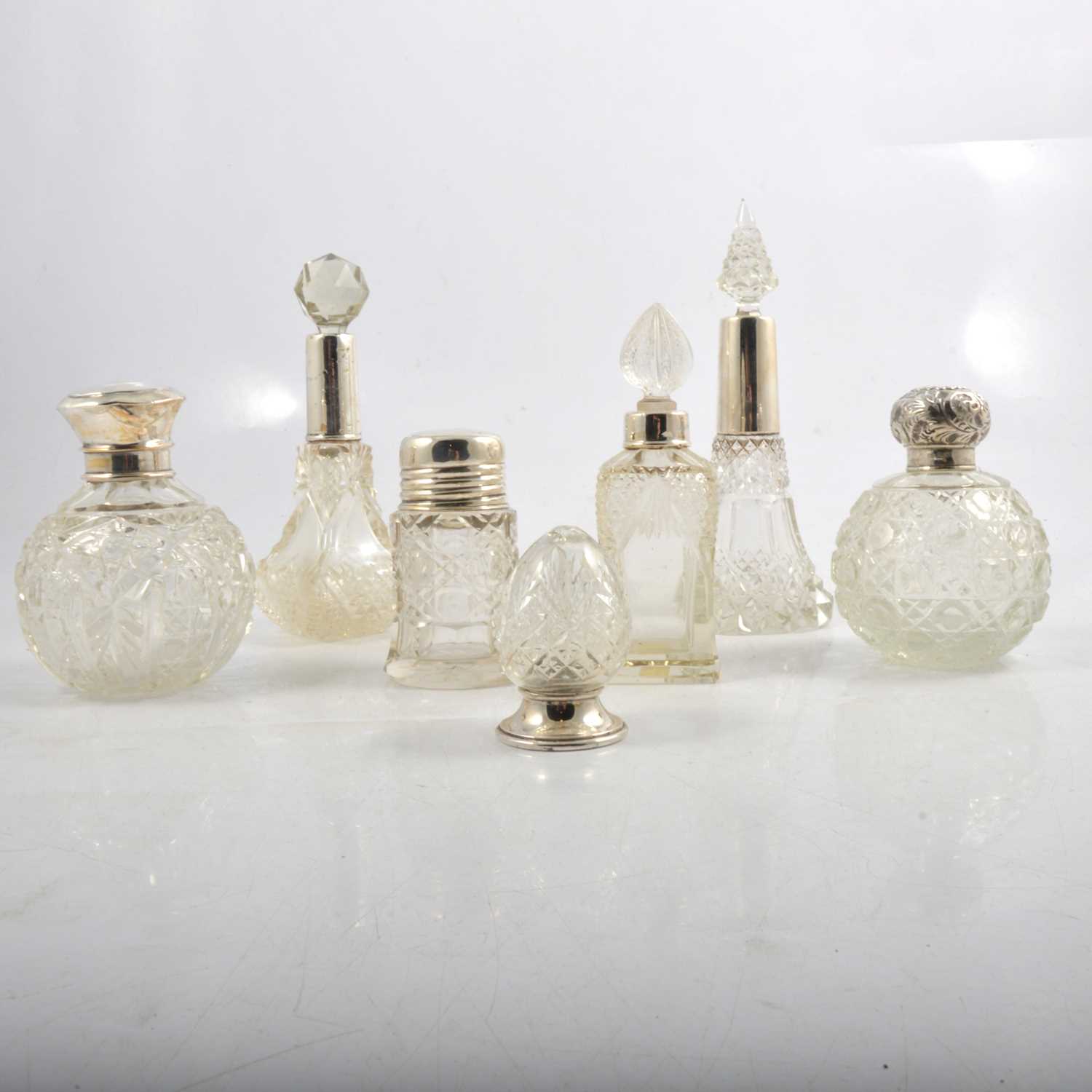 Lot 231 - UPDATED - A silver-bottomed pepperette and six silver-topped / collared cut glass scent bottles.