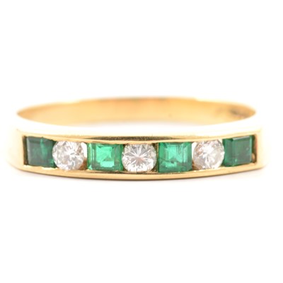 Lot 36 - An emerald and diamond half eternity ring.