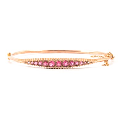 Lot 137 - A 9 carat rose gold half hinged bangle set with eleven synthetic pink stones.
