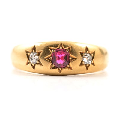 Lot 30 - A diamond and ruby coloured three stone ring.