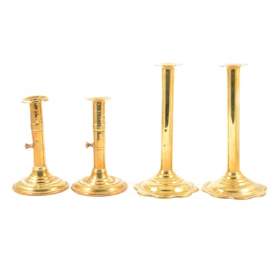 Lot 56 - A pair of tall George III brass push-up candlesticks, and another pair