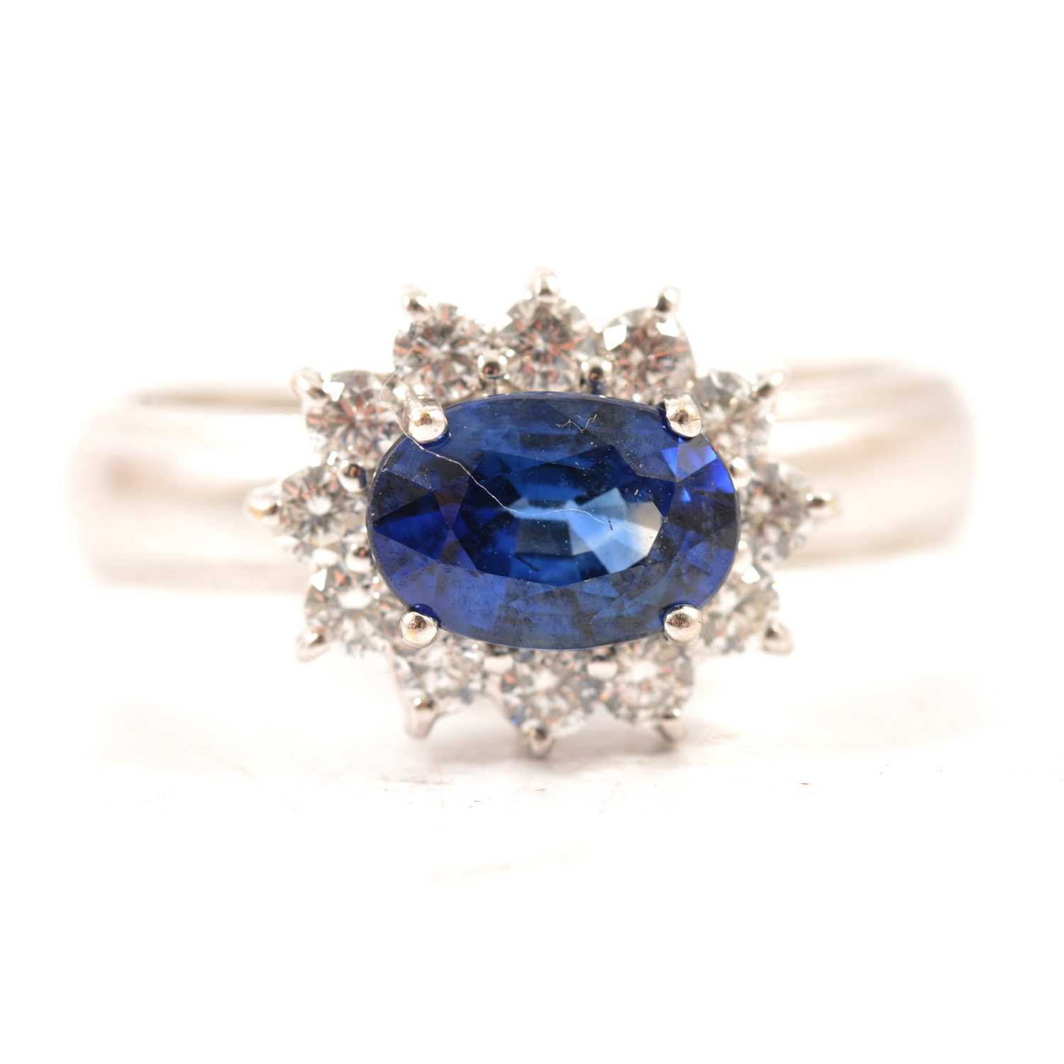 Lot 47 - A sapphire and diamond oval cluster ring.