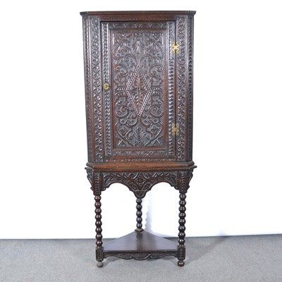 Lot 514 - Carved oak corner cupboard on a related stand