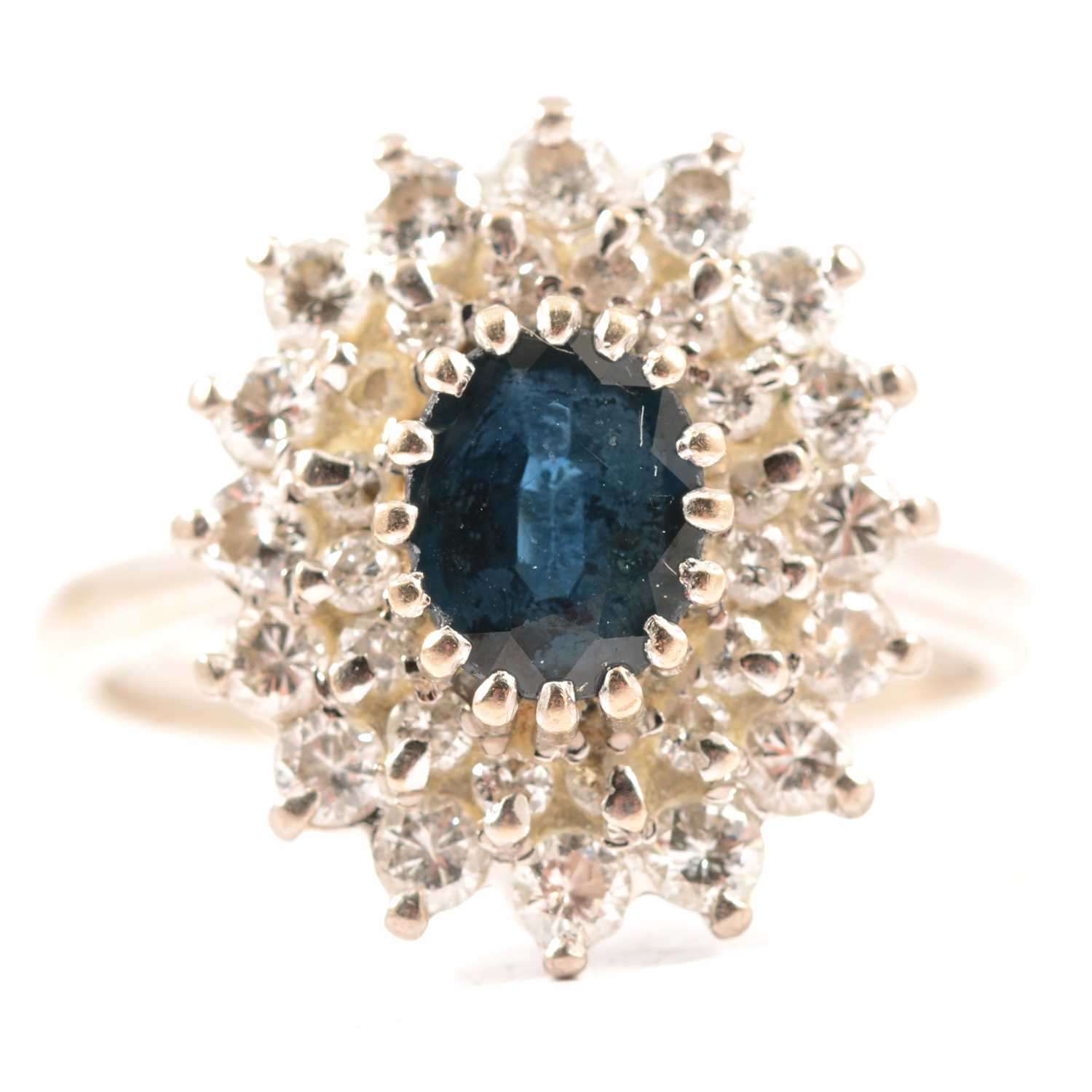 Lot 48 - A sapphire and diamond oval cluster ring.