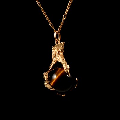 Lot 272 - A tigers eye ball and claw 9 carat gold pendant and chain.