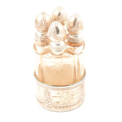 Lot 253 - Four white metal-topped glass scent bottles in a white metal holder