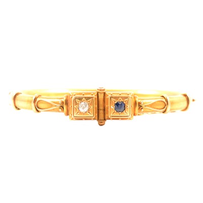 Lot 192 - A yellow metal bangle set with a sapphire and diamond.