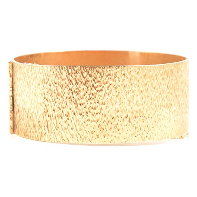 Lot 198 - A 9 carat yellow gold bark texture half-hinged bangle.