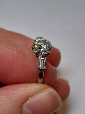 Lot 3 - A diamond solitaire ring with baguette cut shoulders.
